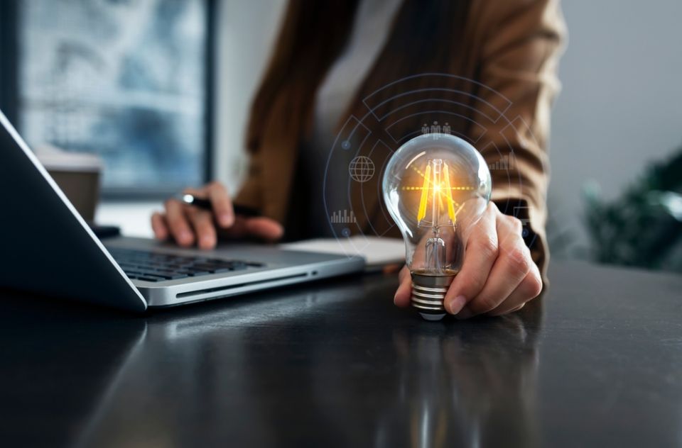 Person holding lamp while working on laptop